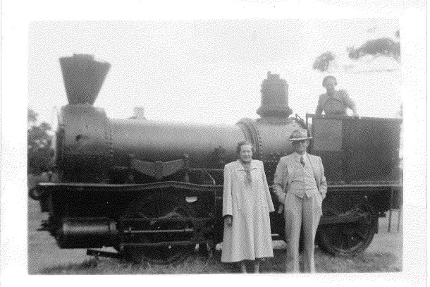 A man, woman, and child in front of the Ballaarat locomotive in Victoria Square, Busselton, in the 1930s.