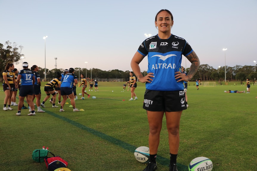 A female rugby player named Anneka Stephens stands with her hands on her hips.