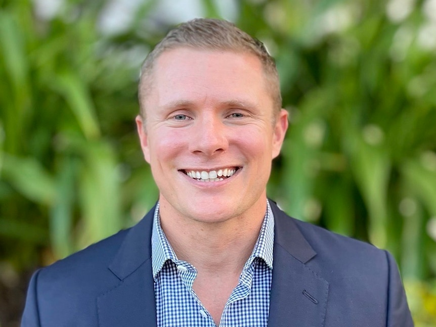 Ben Wheeler smiles into the camera wearing a suit. 