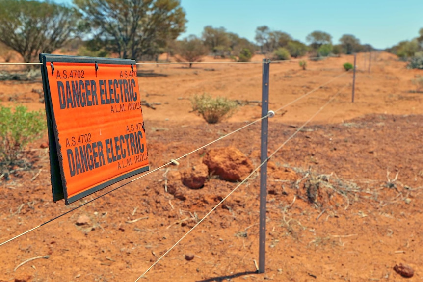 A sign hangs on a fence saying danger electric.