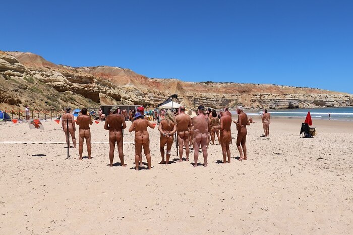 A group of nude people standing on a beach