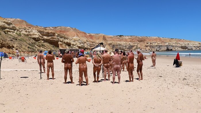 A group of nude people standing on a beach