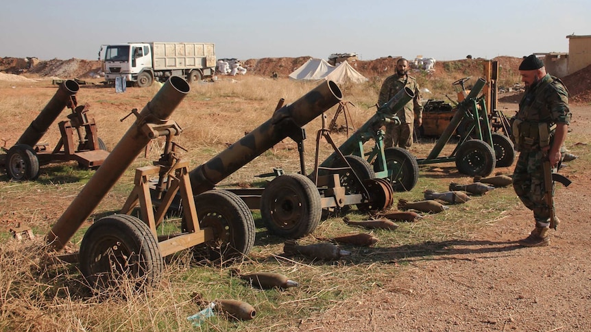 Syrian forces inspect weapons left behind by Islamic State.