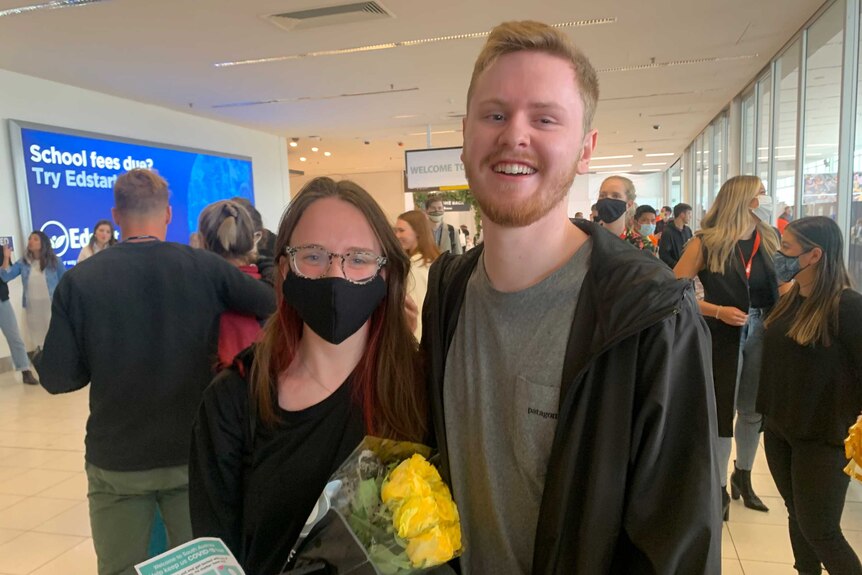 Ash McCall and girlfriend Harriet embrace at Adelaide Airport