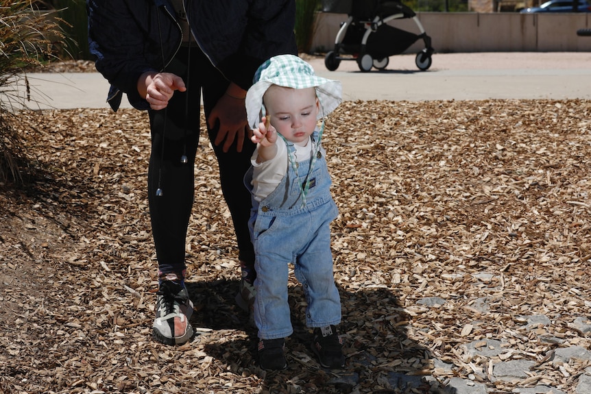 A toddler holds his mother's hand