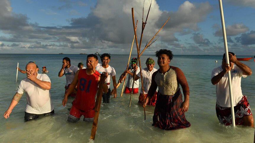 Fishermen walk out of the water with fishing equipment in Tuvalu's capital, Funafuti.