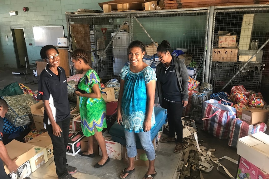 Women smile at the camera as they unload dear.