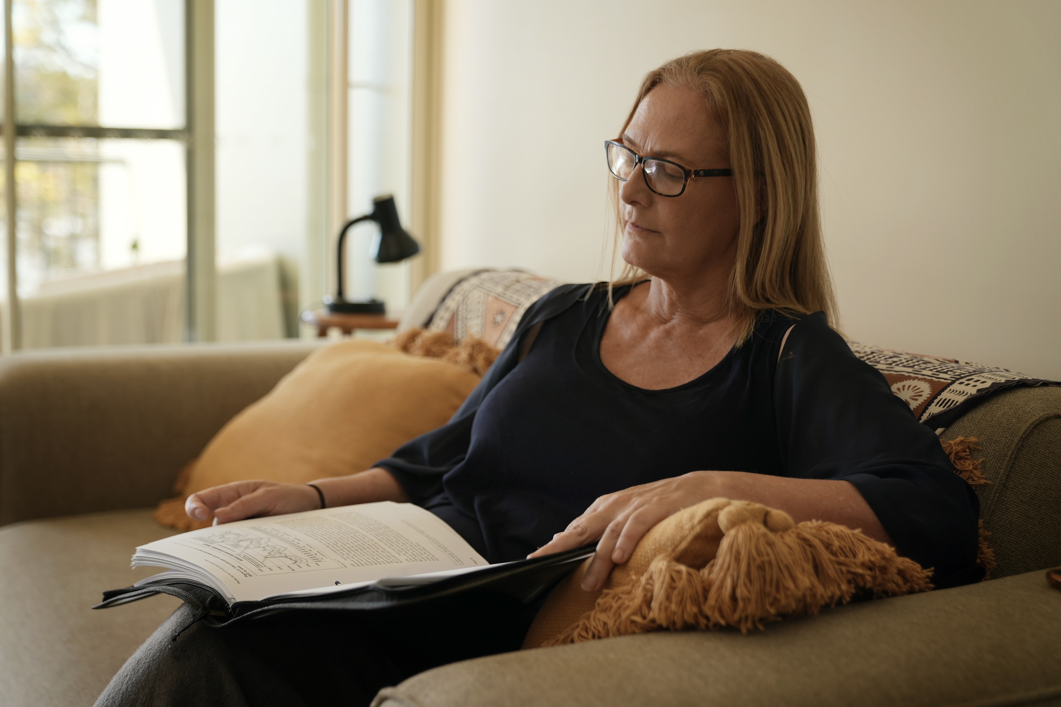 Helen Petaia reading tax documents in her Brisbane home lounge room. 