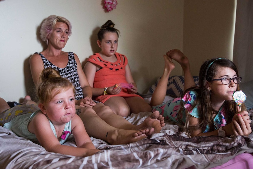 Tonie Adams with her children on a bed.