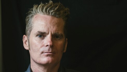 Author James Bradley stands with his arms crossed against a black background.