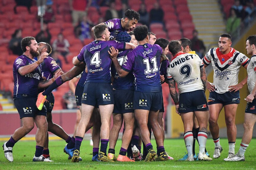 Melbourne Storm NRL players embrace in a group as they celebrate beating Sydney Roosters.