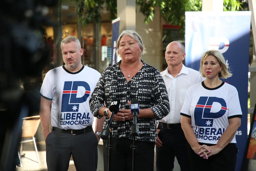 two men and two women stand in front of a microphone