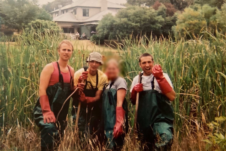 Three young men and one young woman, whose face is blurred, carry out gardening work at the ashram.