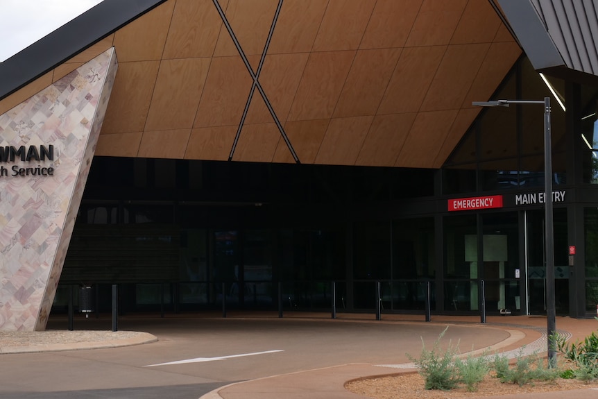 A hospital entrance and carpark with the words "Newman health service" and "Emergency - main entry"