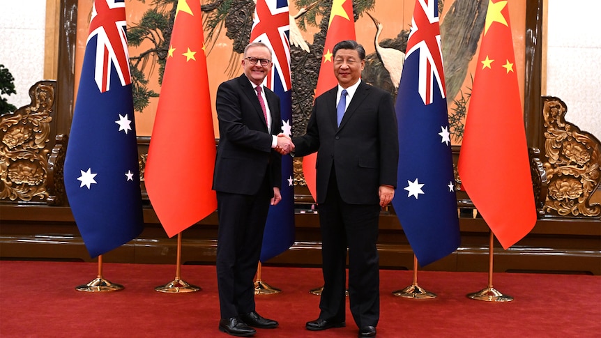Anthony Albanese and Xi Jinping shake hands in front of Australian and Chinese flags.
