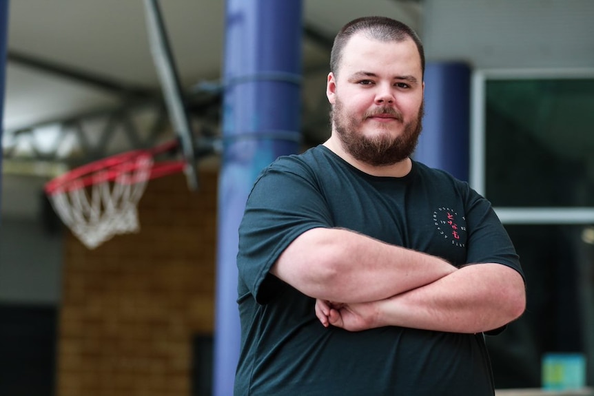 Sam crosses his arms on a basketball court.