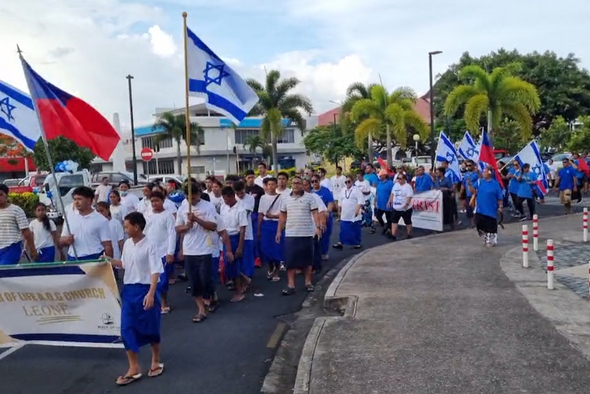 Pro-Israel protestors march in Apia waving Samoan and Israeli flags. 