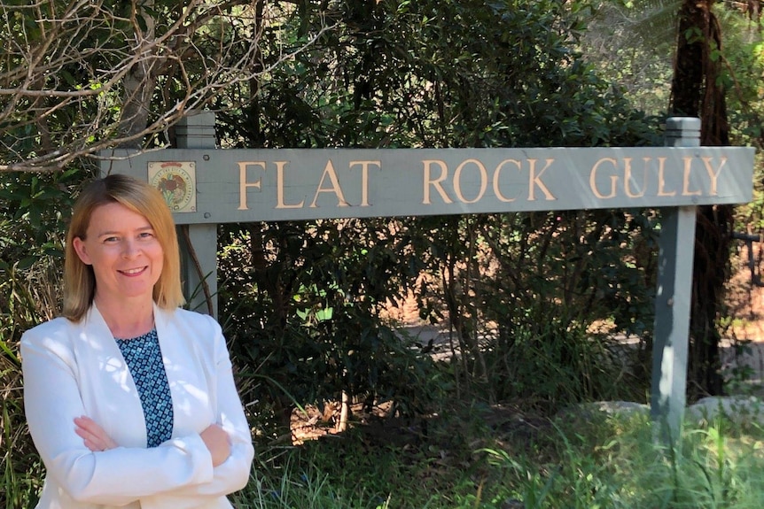 A woman stands near a sign