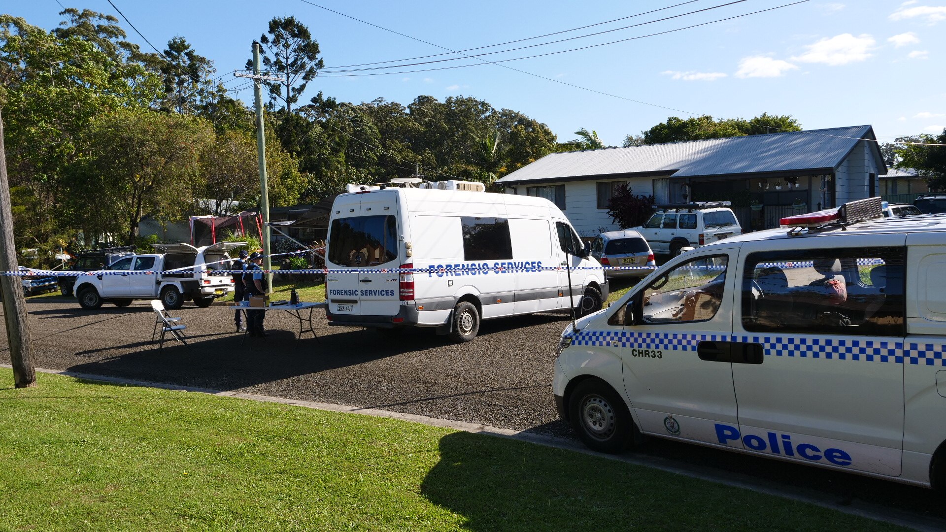 Police vans outside a house roped off with police tape.