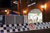 Checkered police tape in the foreground in front of a crime scene curtain at Sydney's Central Station.