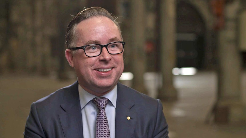 Alan Joyce wears a blue suit, white shirt and purple tie.