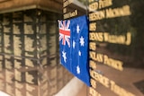 A close up view of an Australian flag on a black wall, covering the newly-added names of three mining casualties.