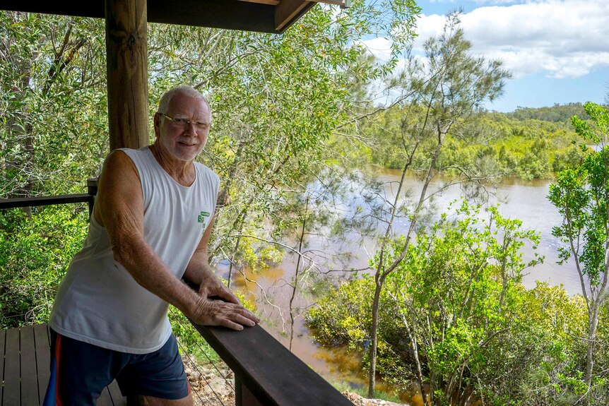 Tim Thornton leaning on a verandah railing looking over at mangroves in the Burrum River.