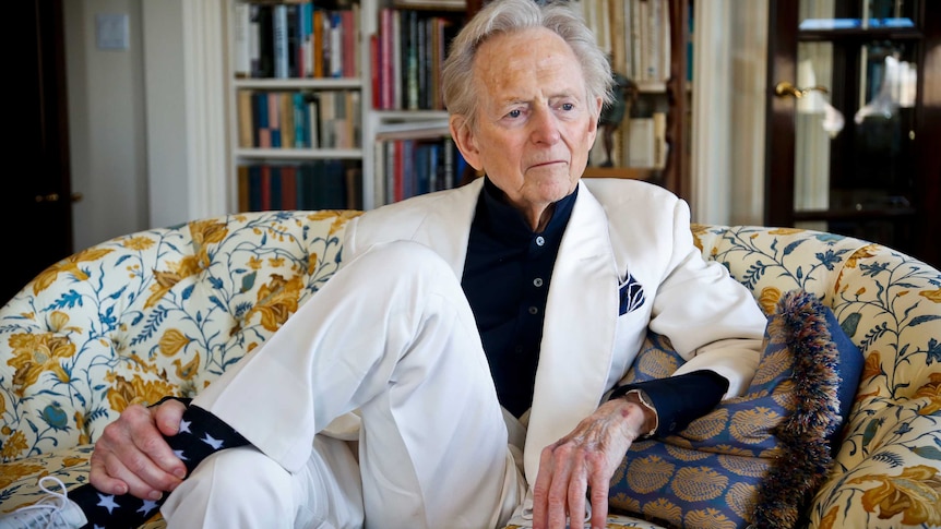 American author and journalist Tom Wolfe sits on a sofa