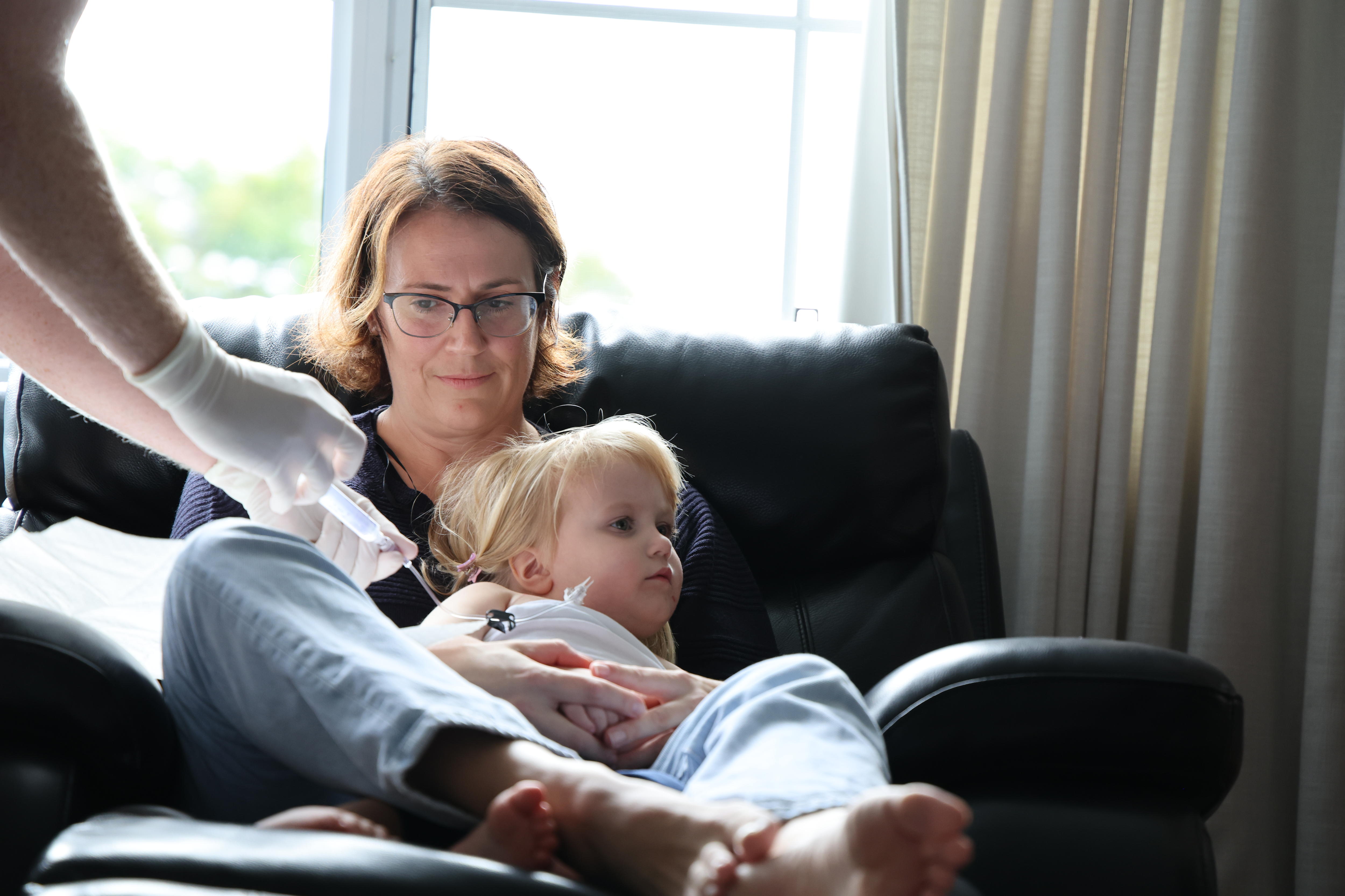 A three year old girl receives a blood infusion while sitting on her mum's lap