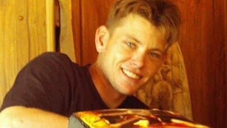 a young man sitting at a table smiles at the camera