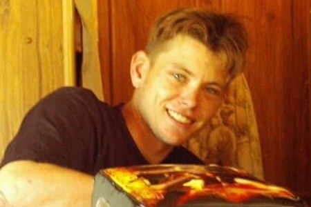 a young man sitting at a table smiles at the camera