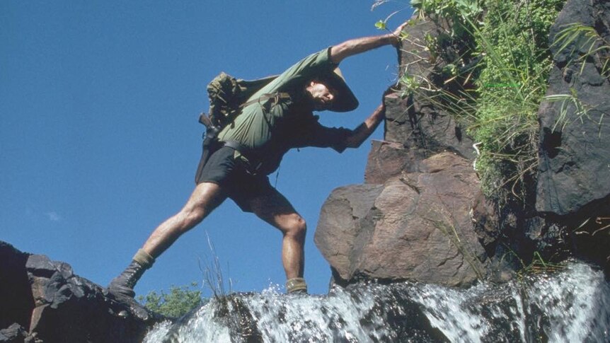 Les Hiddins steps across a small waterfall.