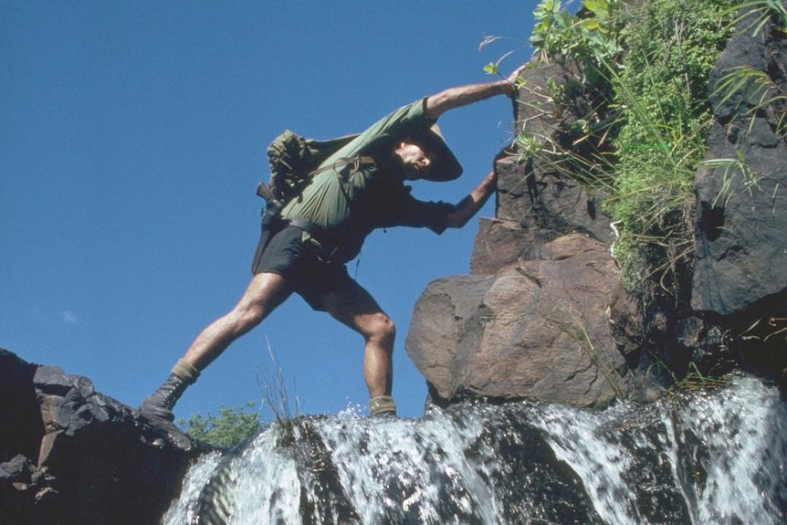 Les Hiddins steps across a small waterfall.