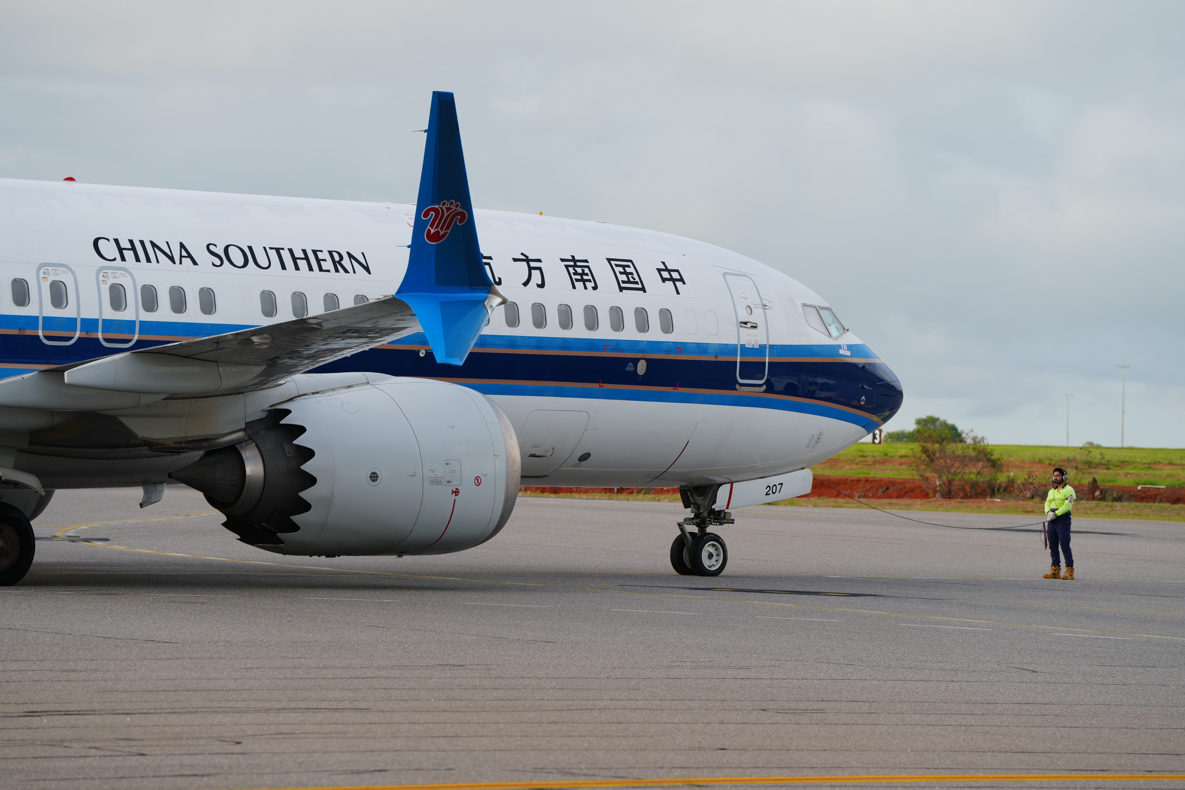 A blue and white plane taxiing towards an airport runway, on the side of the aircraft reads: China Southern Airlines