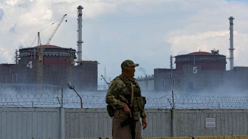 A serviceman with a Russian flag on his uniform stands guard near the Zaporizhzhia Nuclear Power Plant.