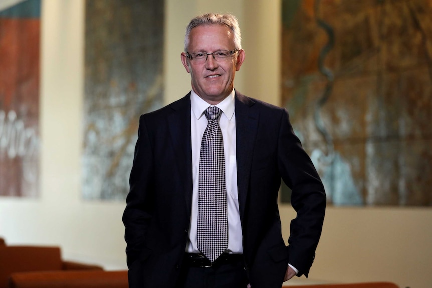 ACT Labor Senator David Smith in the Mural Hall of Parliament House, smiling and wearing glasses.