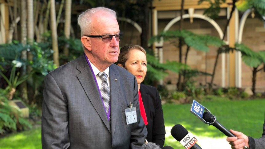 Former police commissioner Bob Atkinson and Child Safety Minister Di Farmer in front of microphones.
