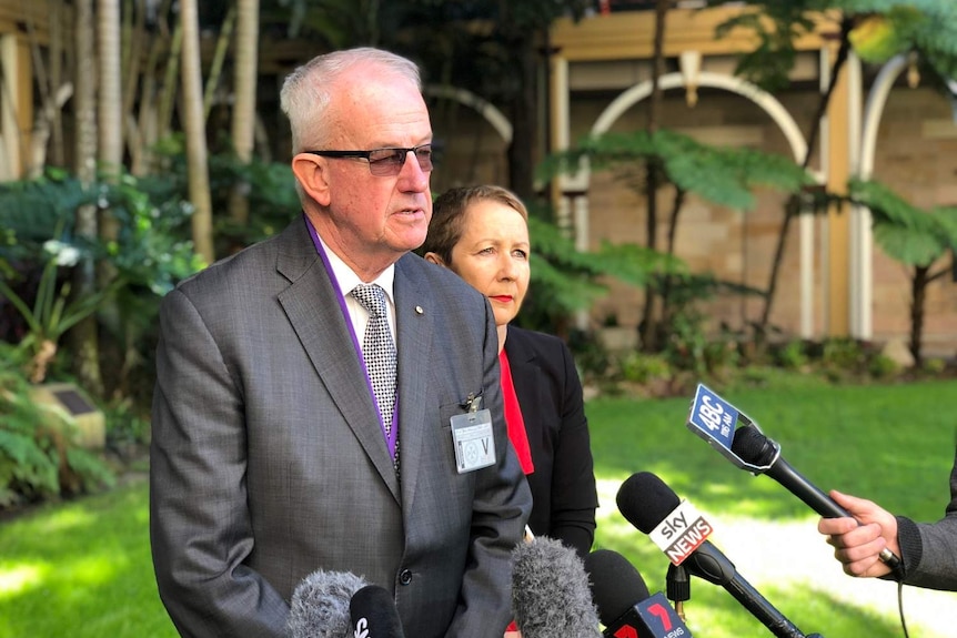 Former police commissioner Bob Atkinson and Child Safety Minister Di Farmer in front of microphones.