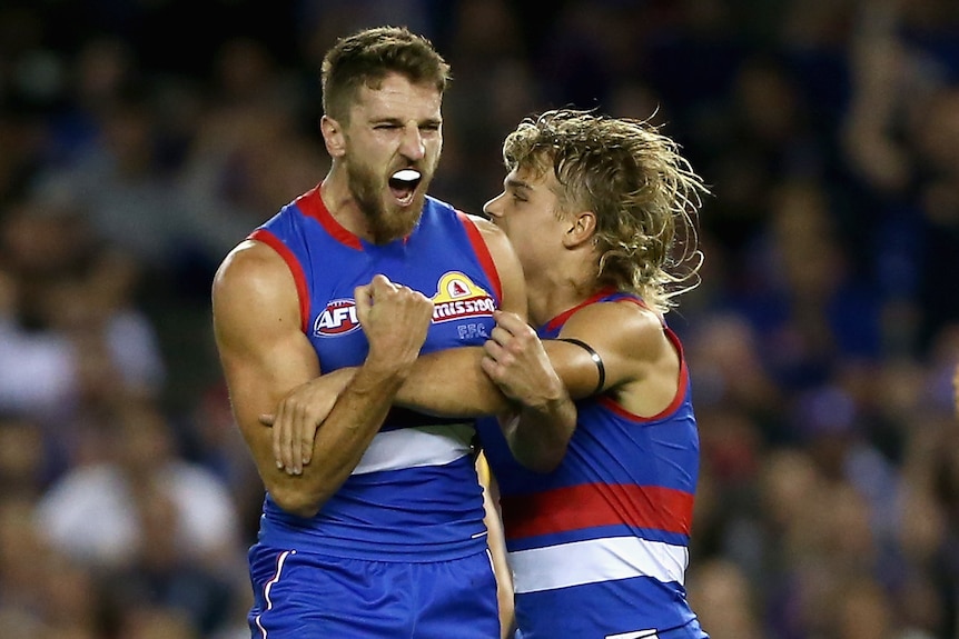 Two Western Bulldogs AFL players embrace as they celebrate a goal against West Coast.
