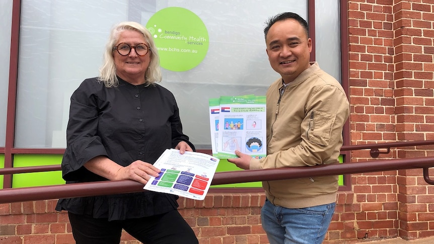 A woman and man holding information leaflets in front of the Bendigo Health Community Services building.