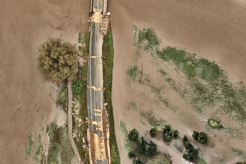 aerial view of a damaged road with brown floodwaters either side