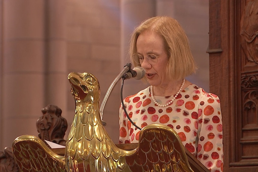 jeannette young speaks from behind a lectern into a microphone in a church