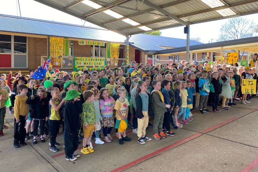 A school assembly of primary school students dressed in green and gold