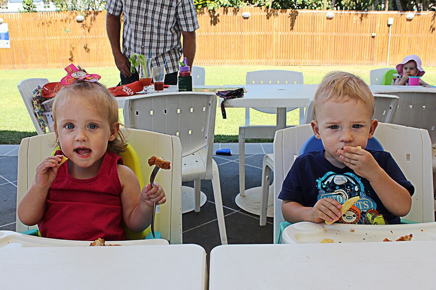 Two small children eating at a table