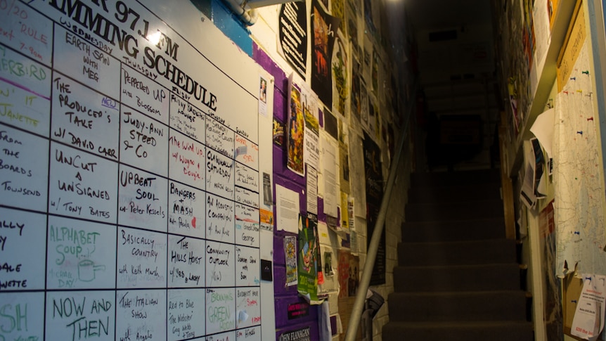 A staircase, walls lined with posters and notices.