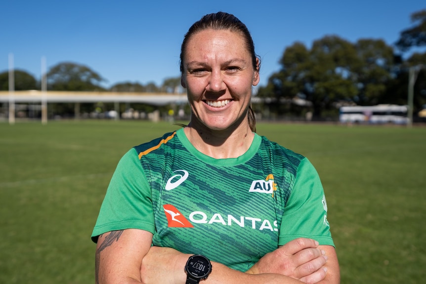 An Australian women's rugby sevens player smiles with her arms folded and a watch on her left hand.