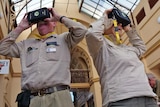 Two people wear virtual reality headsets inside old building with glass roof