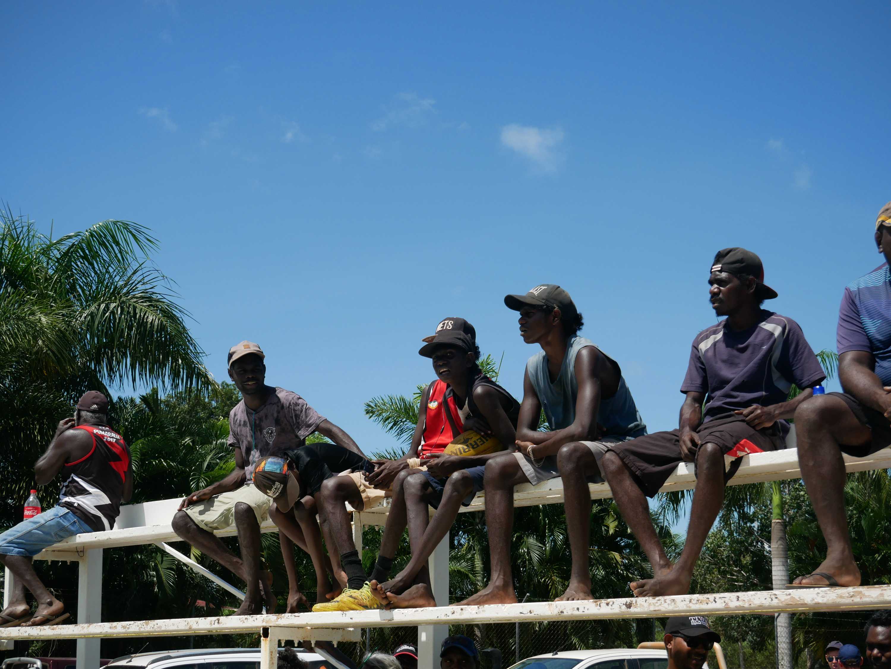A group of teenagers sit on the bleachers to watch the Tiwi Islands football grand final.