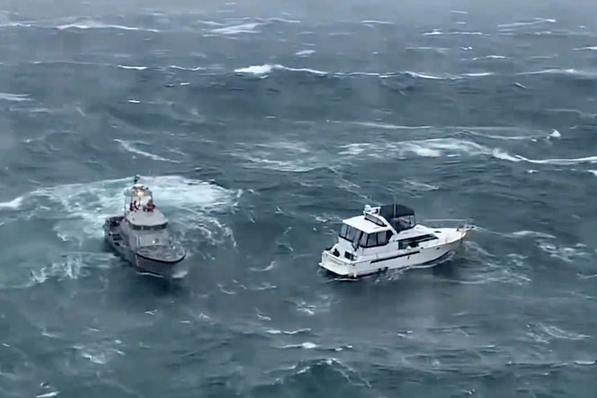 A Coast Guard ship, left, attempts to a rescue a distressed yacht in heavy seas.