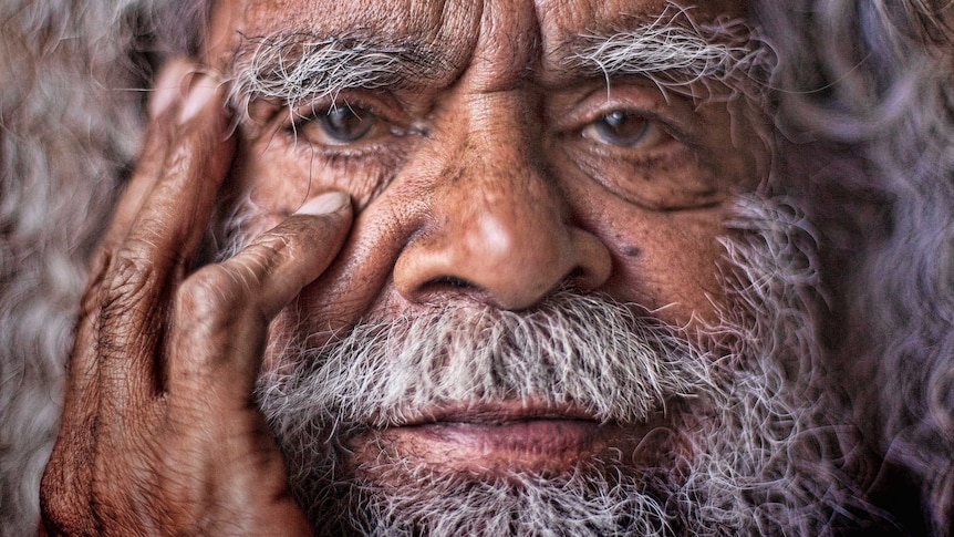 An extreme close-up of Uncle Jack Charles' holding his hand to his face.